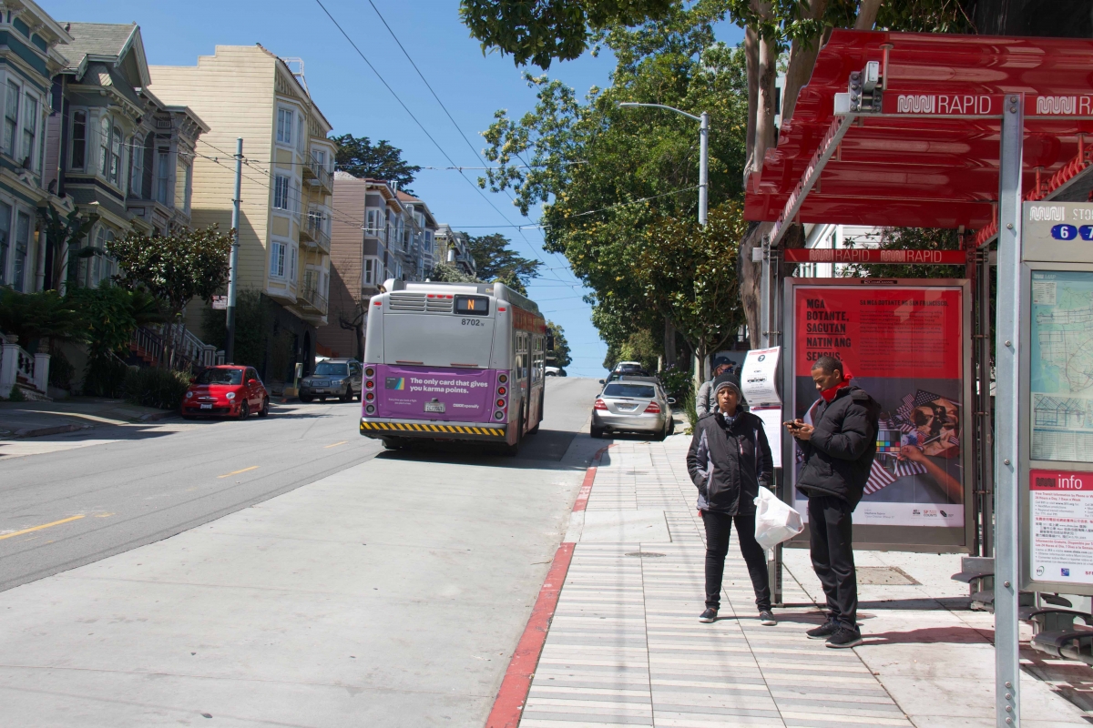 Two people wait for another bus after not boarding an N Judah bus on Haight Street at Divisadero Street on April 7. Service for the 7 Haight/Noriega, which normally stopped there, was cut on April 7, and for the 6 Haight/Parnassus on April 8. 