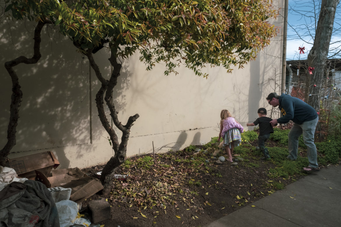 Children play in the green patch outside Merced Dominguez’s recreational vehicle. A father pulls his son away from her plants and garden decorations. He tells his children it is time to go and to not touch anything else.