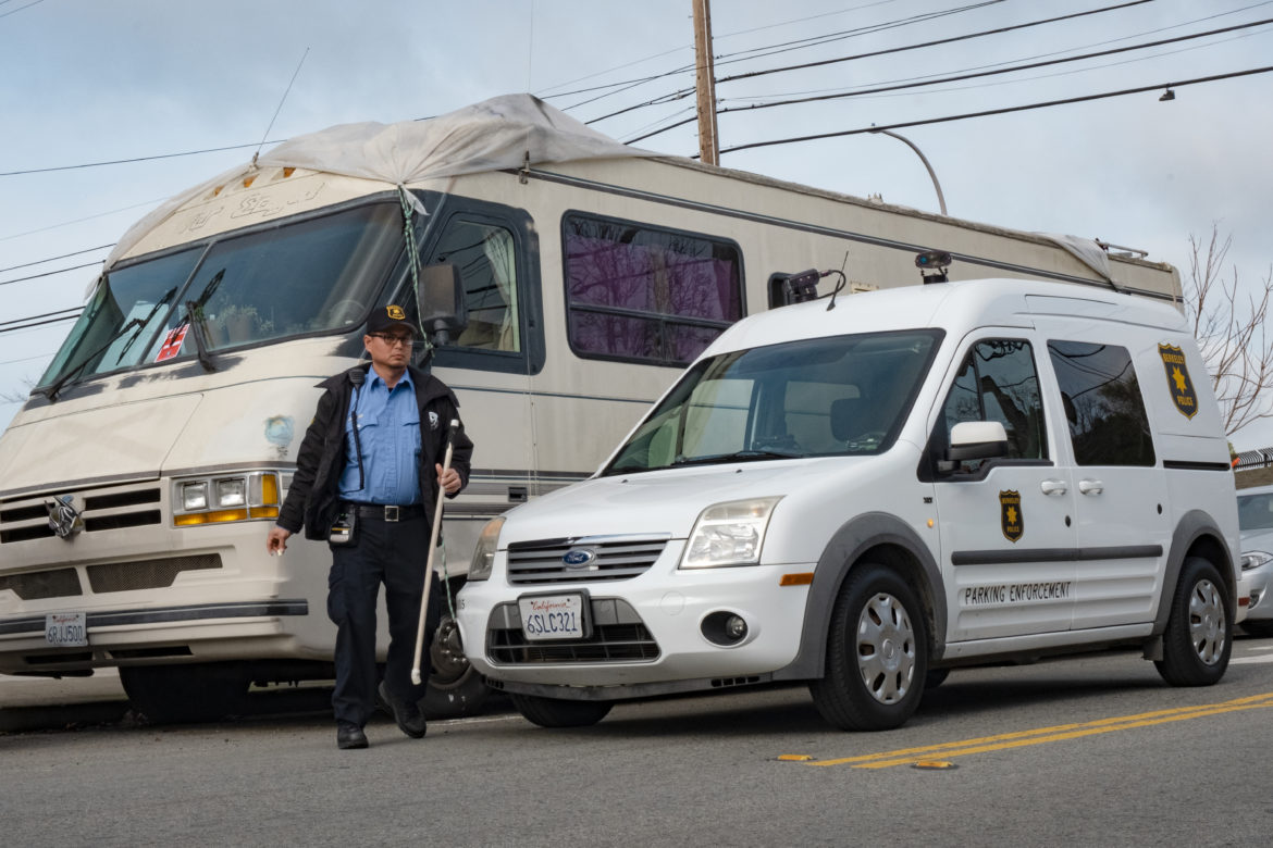 A Berkeley parking enforcement officer chalks the tires of a recreational vehicle so he can determine whether it stays parked in the same spot in West Berkeley for more than 72 hours. Parking enforcement appeared weekly in the winter, but vehicle residents avoided citations by moving across the street or a few feet forward to reset the parking clock.
