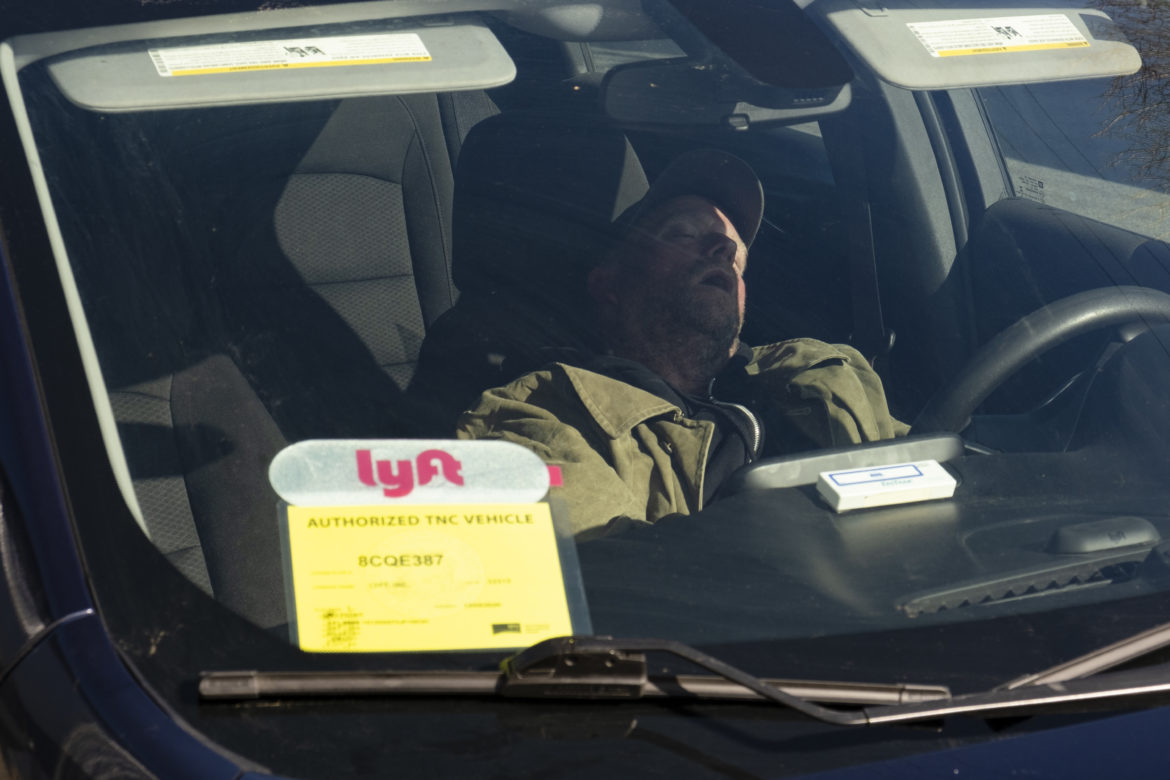 On a Saturday morning, Nelson sleeps inside his rented Lyft vehicle after an evening shift in the city. In late December, he began working for the ride-hailing company, helping him pay bills and buy food. The driving gig also helped him access resources and amenities around the city: restrooms, showers, laundry and electricity.