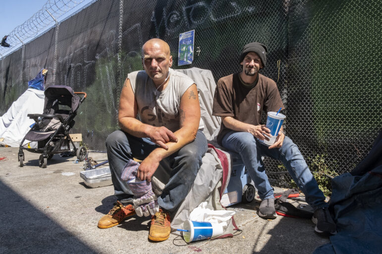 Vinny Vizgaudis, left, and Max sit amid their possessions and some debris.