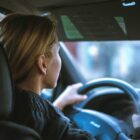 A woman sitting in a car, behind the steering wheel.