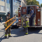 Firefighters handle a ladder and other gear in the field.