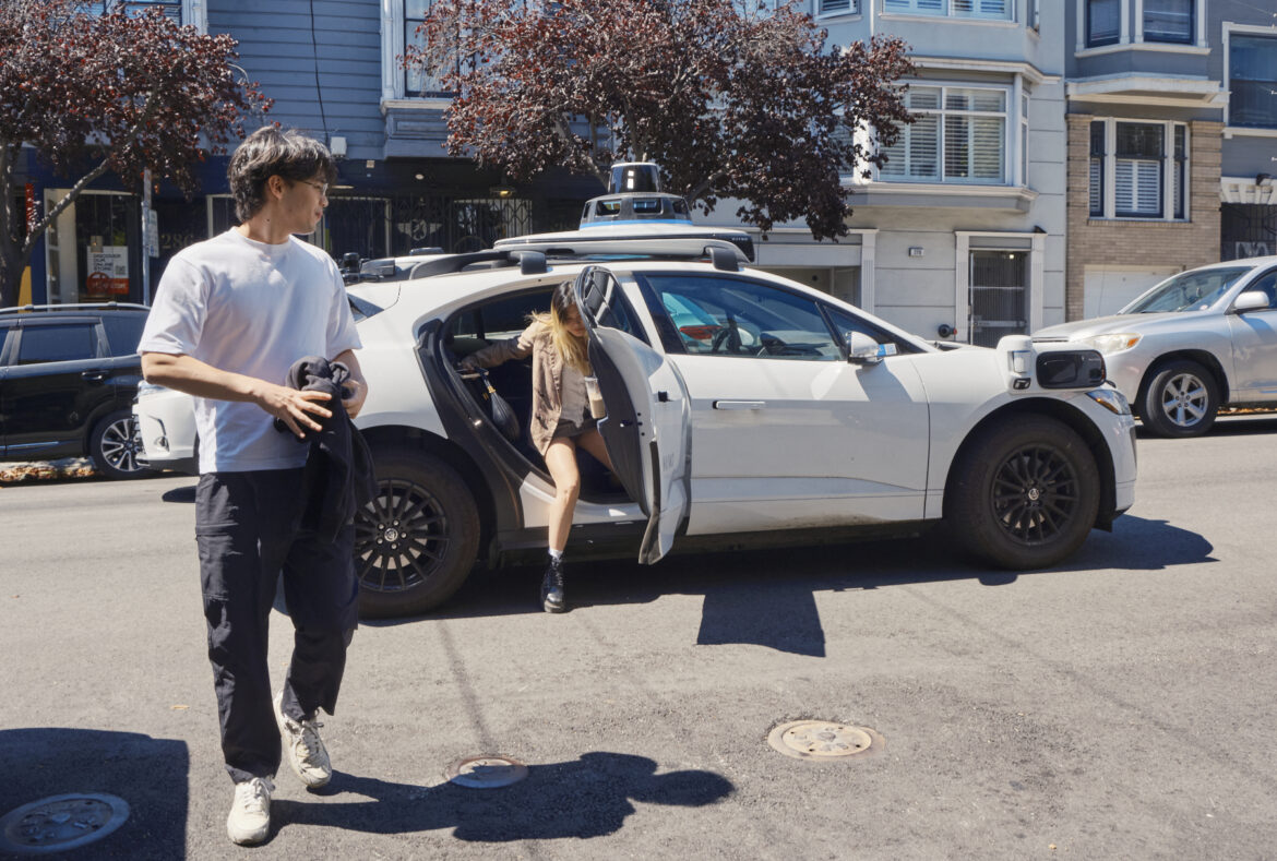 Passengers disembark a Waymo vehicle.