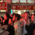 A crowd of people watch a music show, their faces lit, at Mayor Daniel Lurie’s inaugural party in Chinatown.